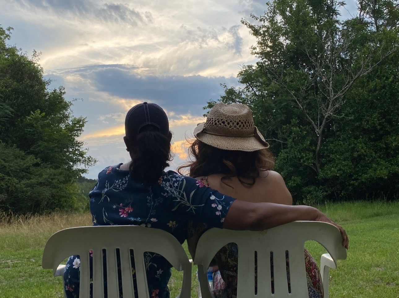 Two people sitting together outdoors looking over the land at sunset